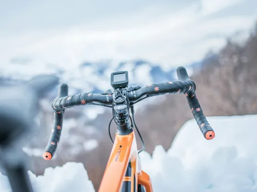 Oranssi py&ouml;r&auml; lumisessa maisemassa, ohjaustanko etualalla.